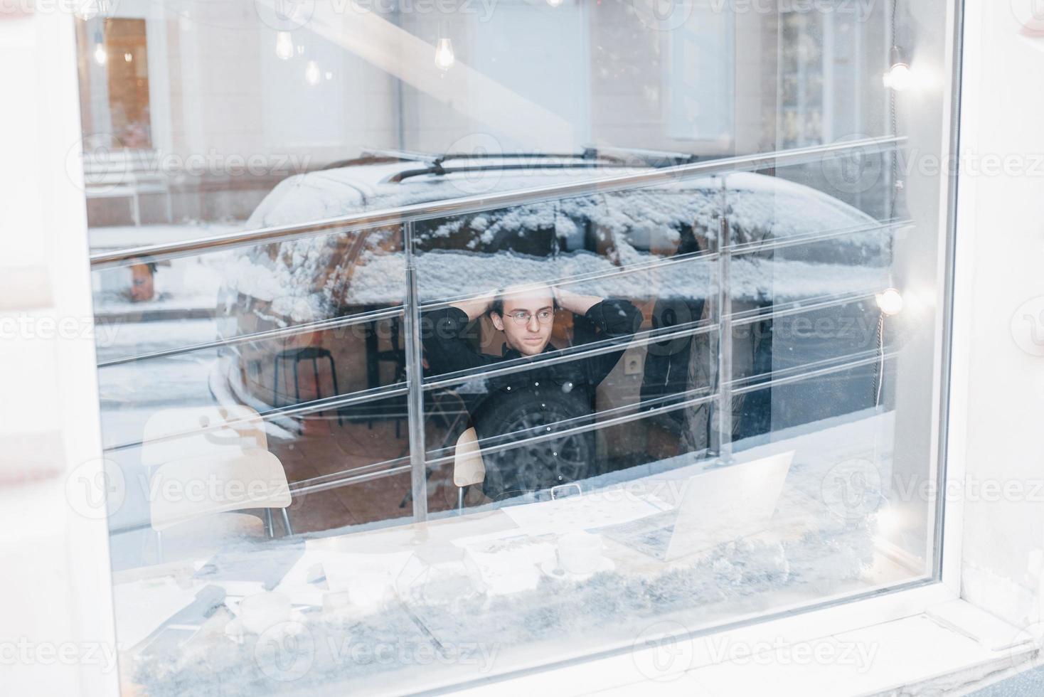 Young man drinking coffee in cafe looking out the window photo