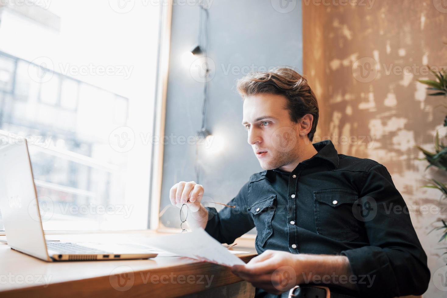 Relajado joven profesional navegando por internet en su portátil en un café foto