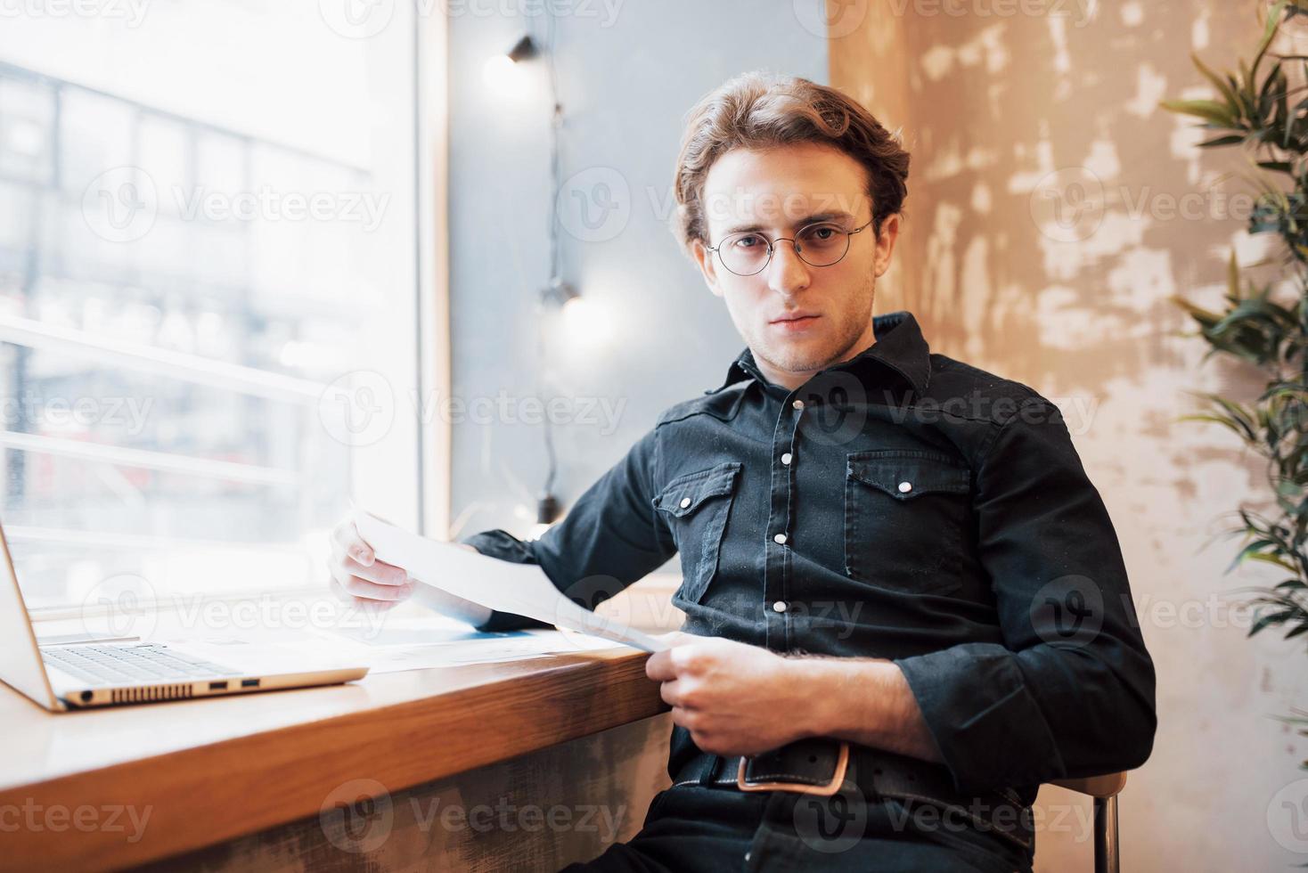 Relaxed young professional surfing the Internet on his laptop in a cafe photo