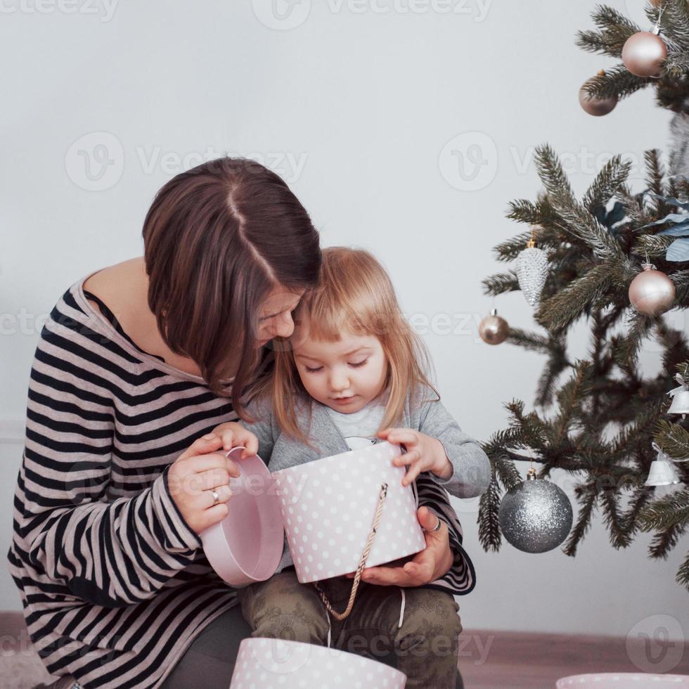 feliz madre de familia y el bebé decoran el árbol de navidad foto