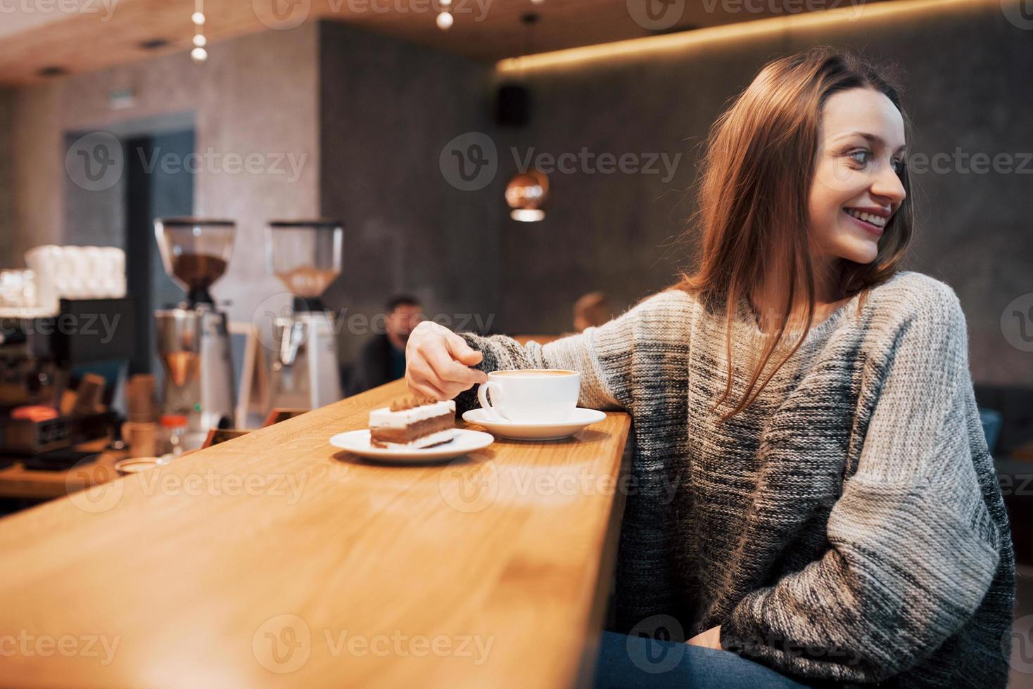 Bastante joven sentada en el café con una taza de té foto