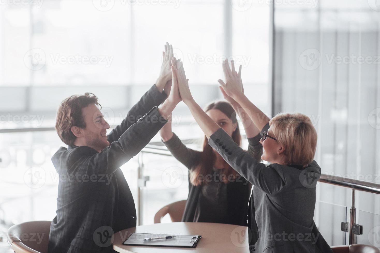 Start up business. Group of young architect at office. group of business partners giving high five photo