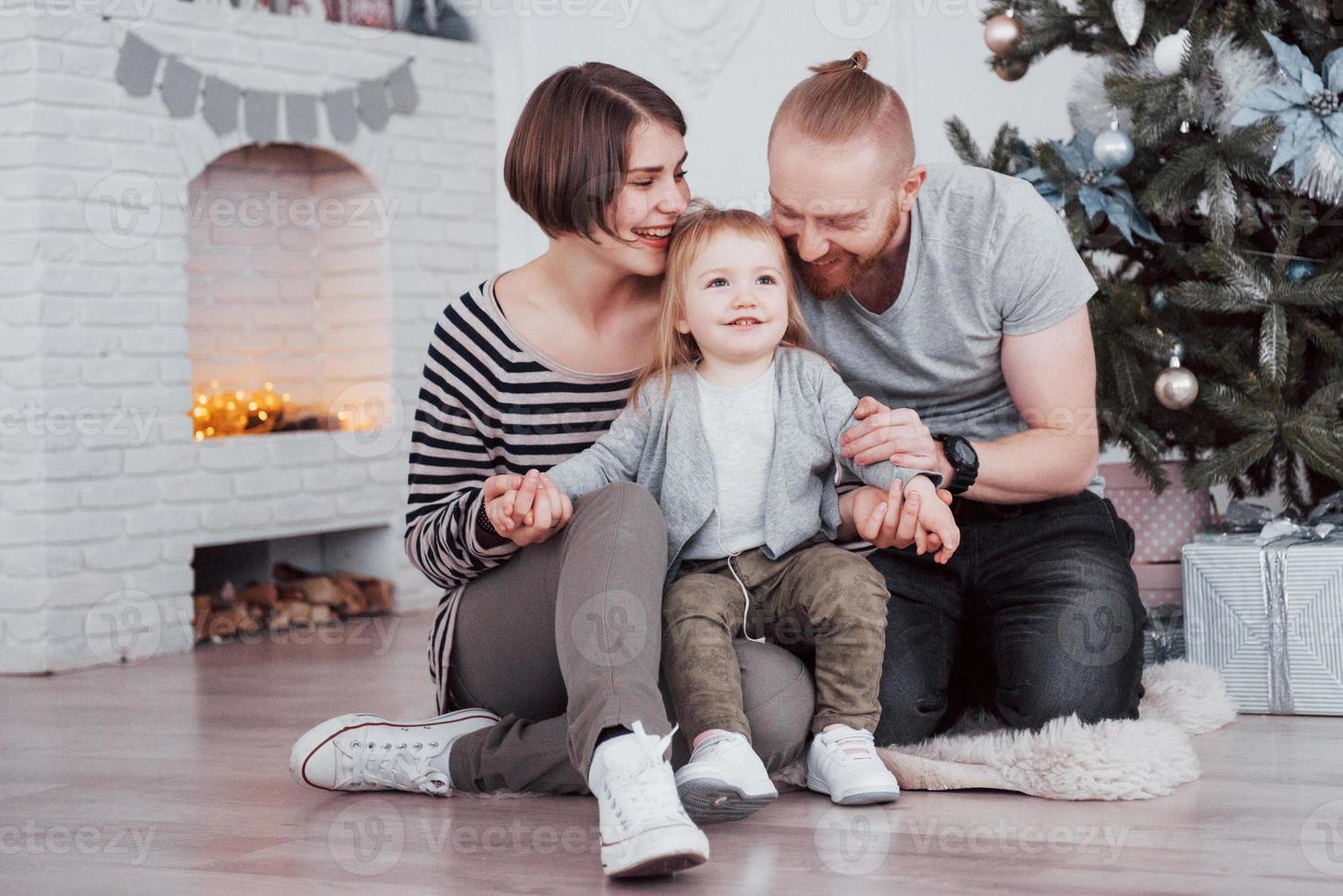 Happy family at christmas in morning opening gifts together near the fir tree. The concept of family happiness and well-being photo