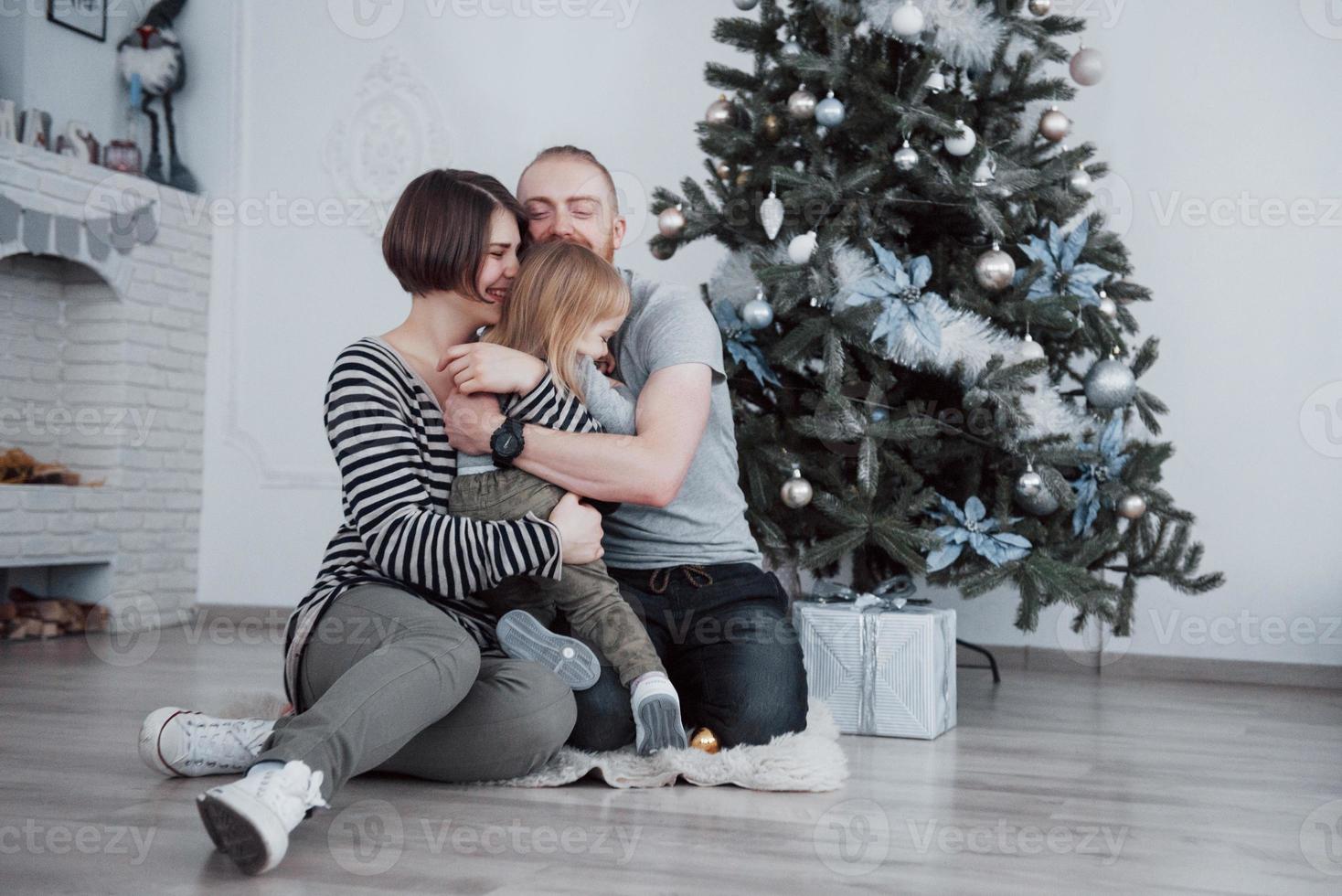Happy family at christmas in morning opening gifts together near the fir tree. The concept of family happiness and well-being photo