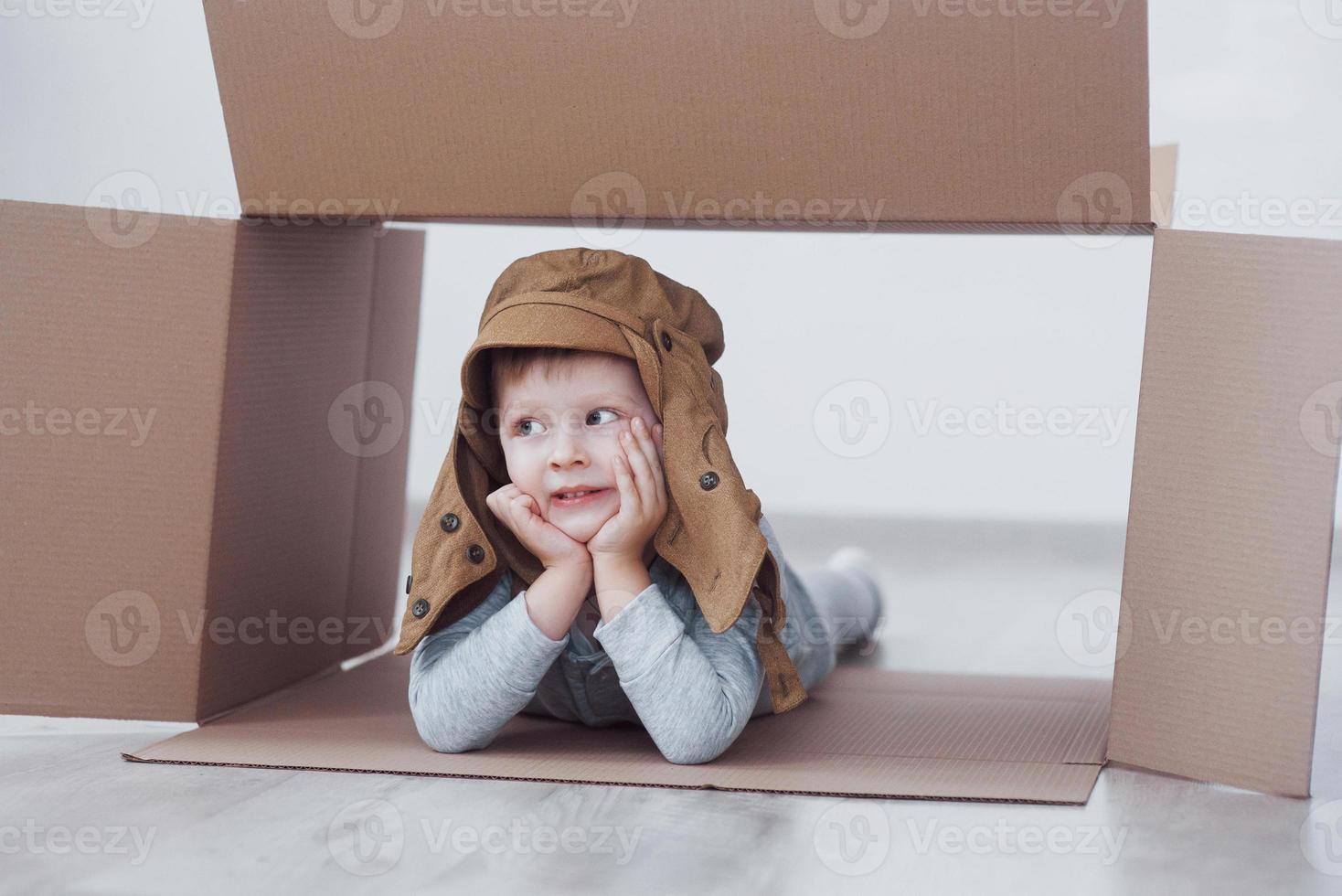 niño niño en edad preescolar jugando dentro de la caja de papel. infancia, reparaciones y nuevo concepto de casa. foto
