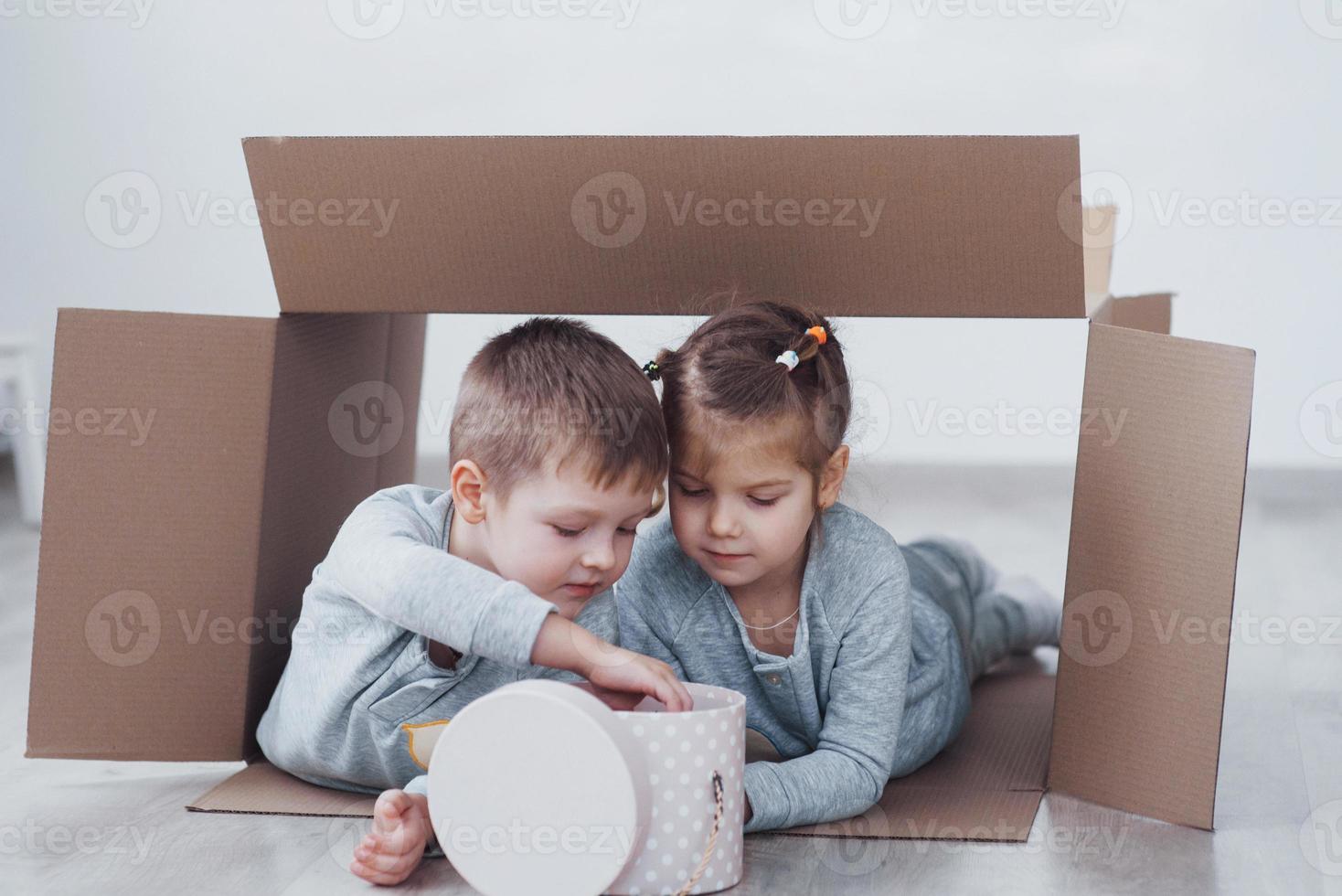 dos niños pequeños, niño y niña jugando en cajas de cartón. foto de concepto. los niños se divierten