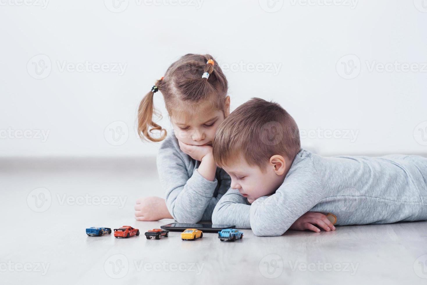 Children using digital gadgets at home. Brother and sister on pajamas watch cartoons and play games on their technology tablet photo