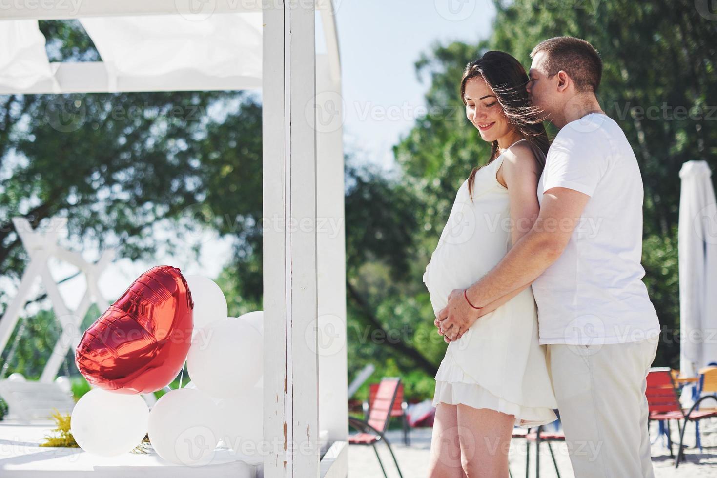 Happy and young pregnant couple hugging in nature photo