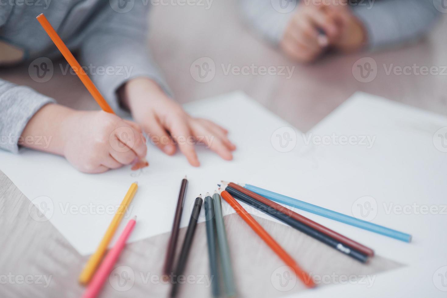 Children lie on the floor in pajamas and draw with pencils. Cute child painting by pencils.Hand of child girl and boy draw and paint with crayon. Close up view photo