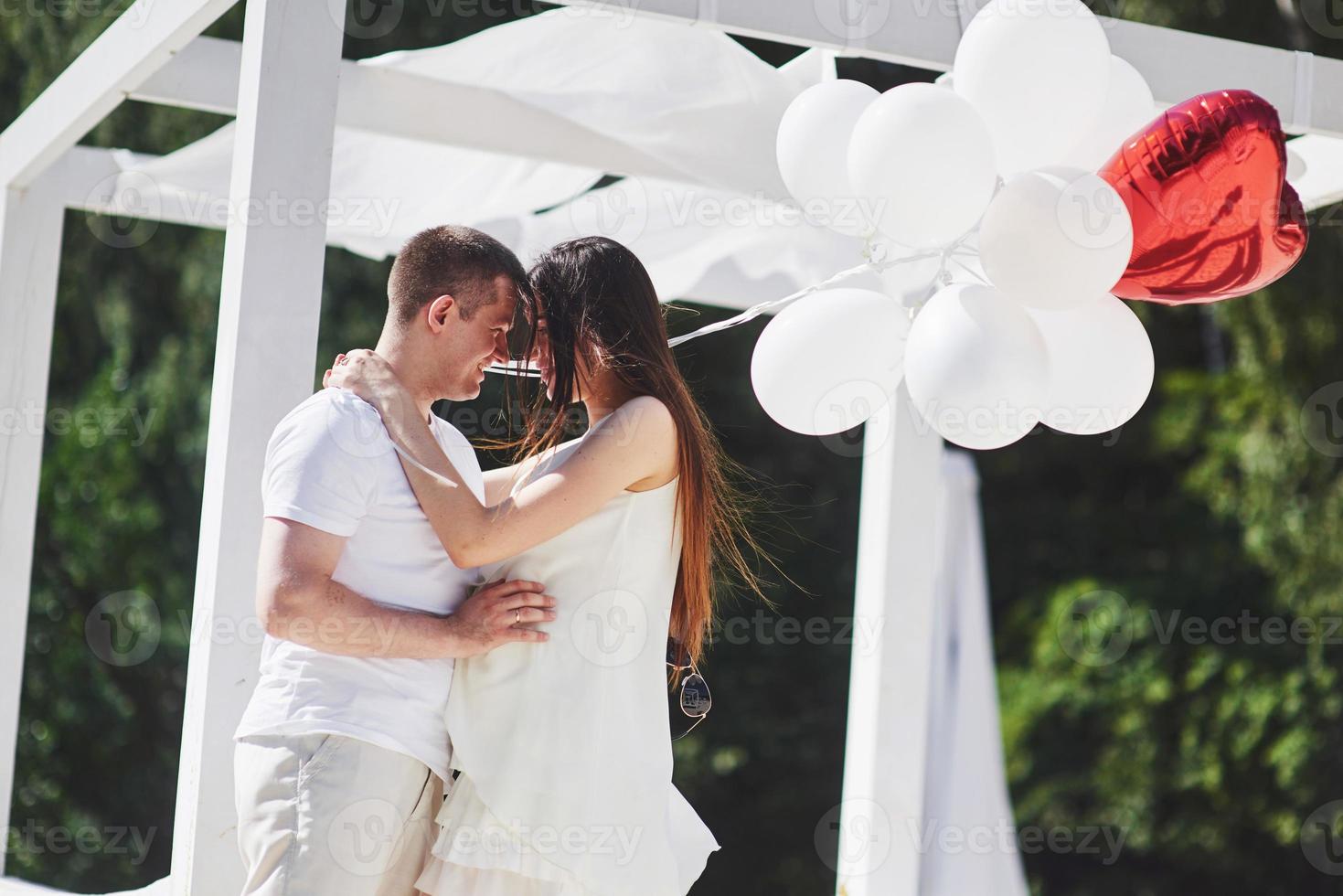 Happy and young pregnant couple hugging in nature photo