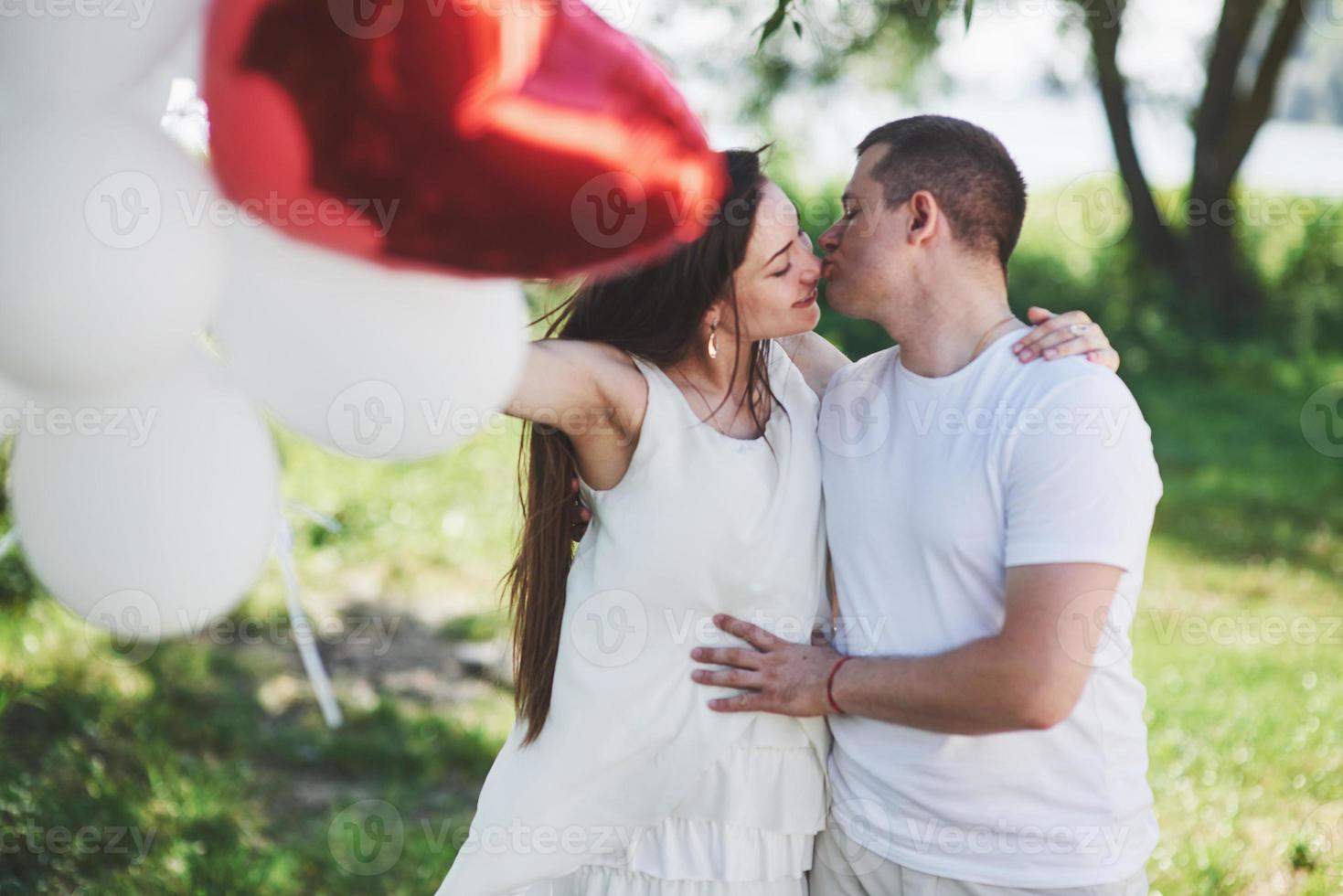 feliz y joven pareja embarazada abrazándose en la naturaleza. momentos romanticos foto