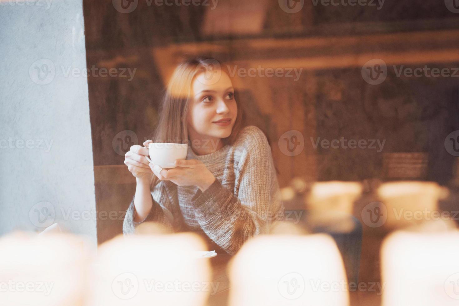 pretty young woman sitting in the cafe with a cup of tea photo