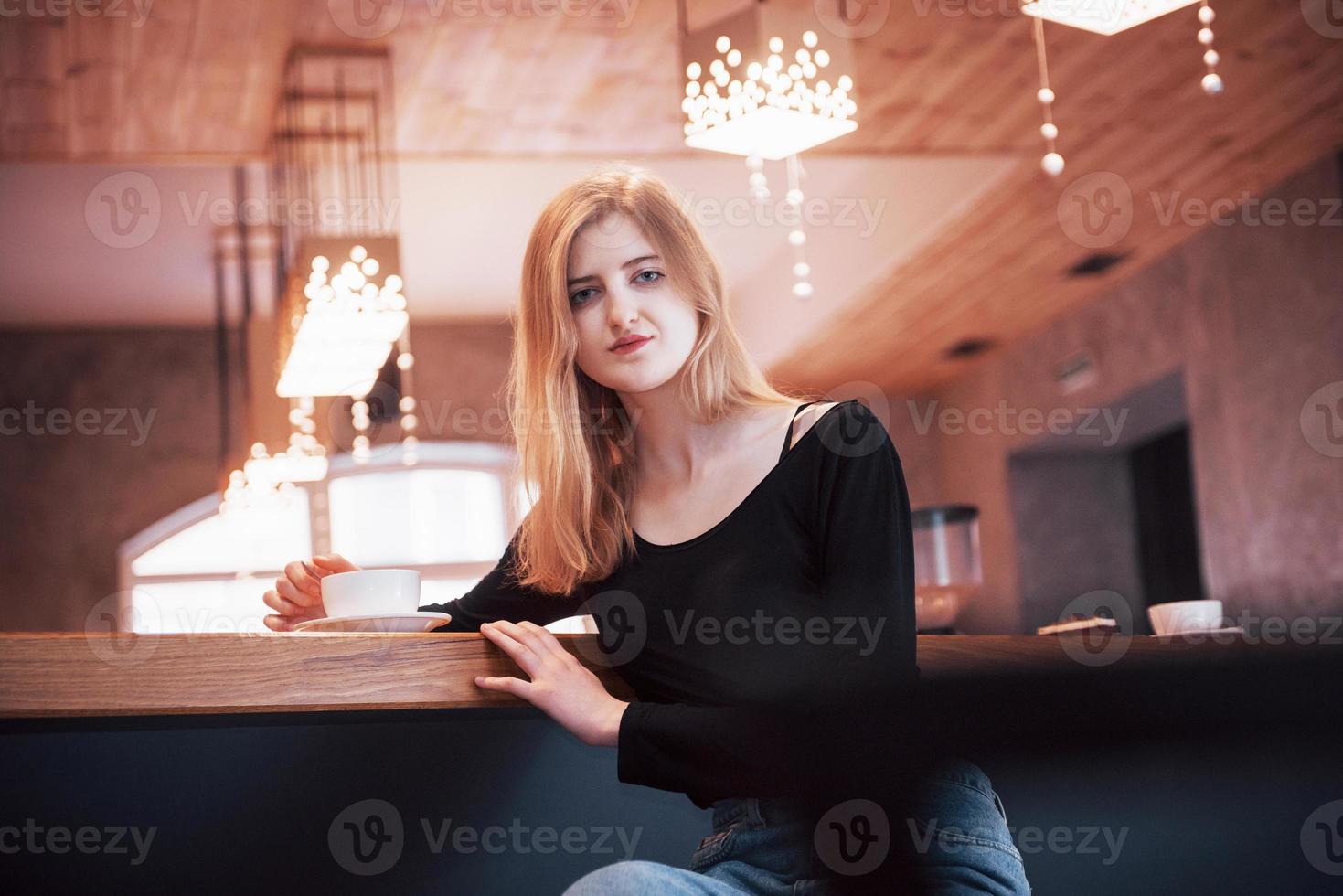 Happy smiling young woman using phone in a cafe. Beautiful girl in trendy spring colors photo