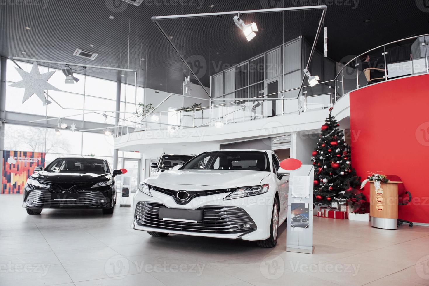 New shining beautiful cars stand near desk reception in car shop photo