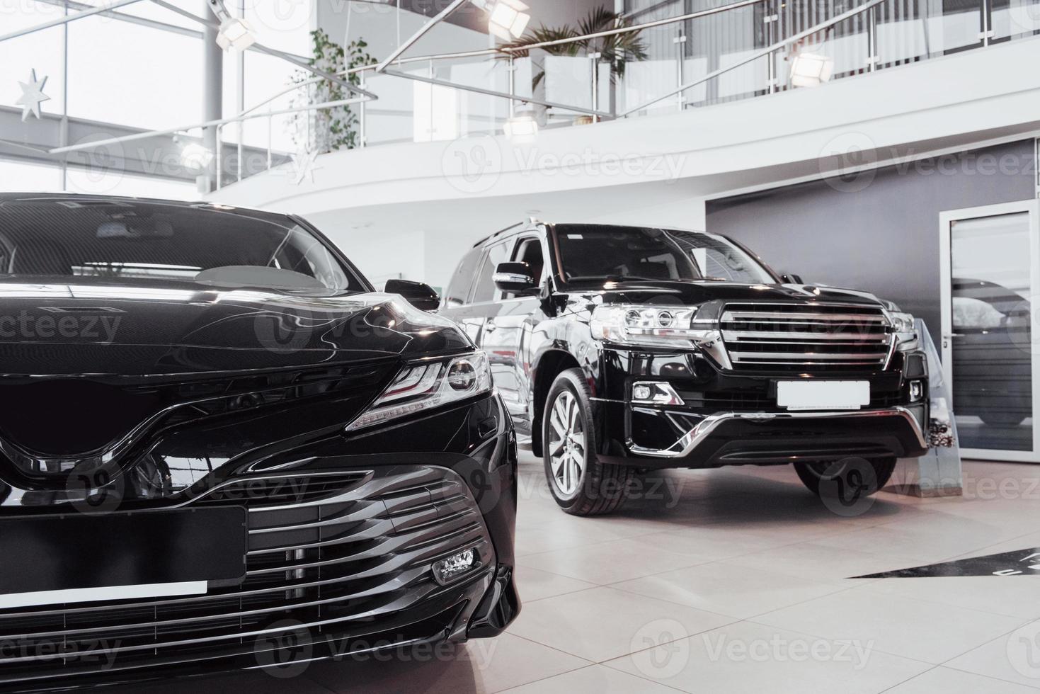 New shining beautiful cars stand near desk reception in car shop photo