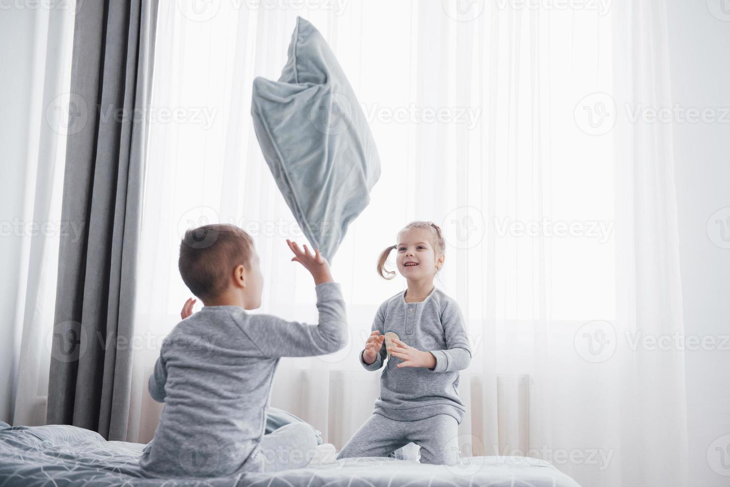 Children in soft warm pajamas playing in bed photo