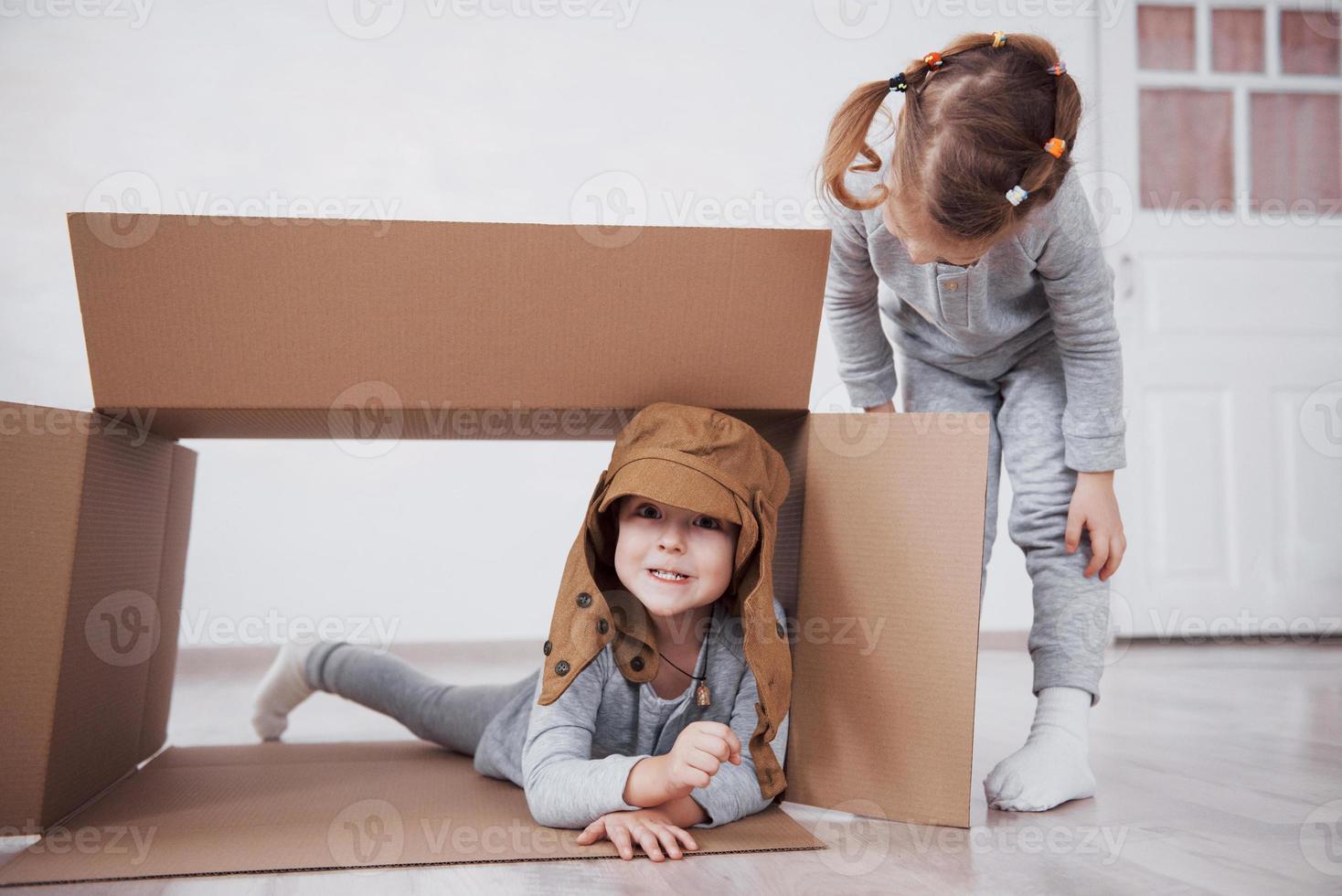 Baby brother and child sister playing in cardboard boxes in nursery photo