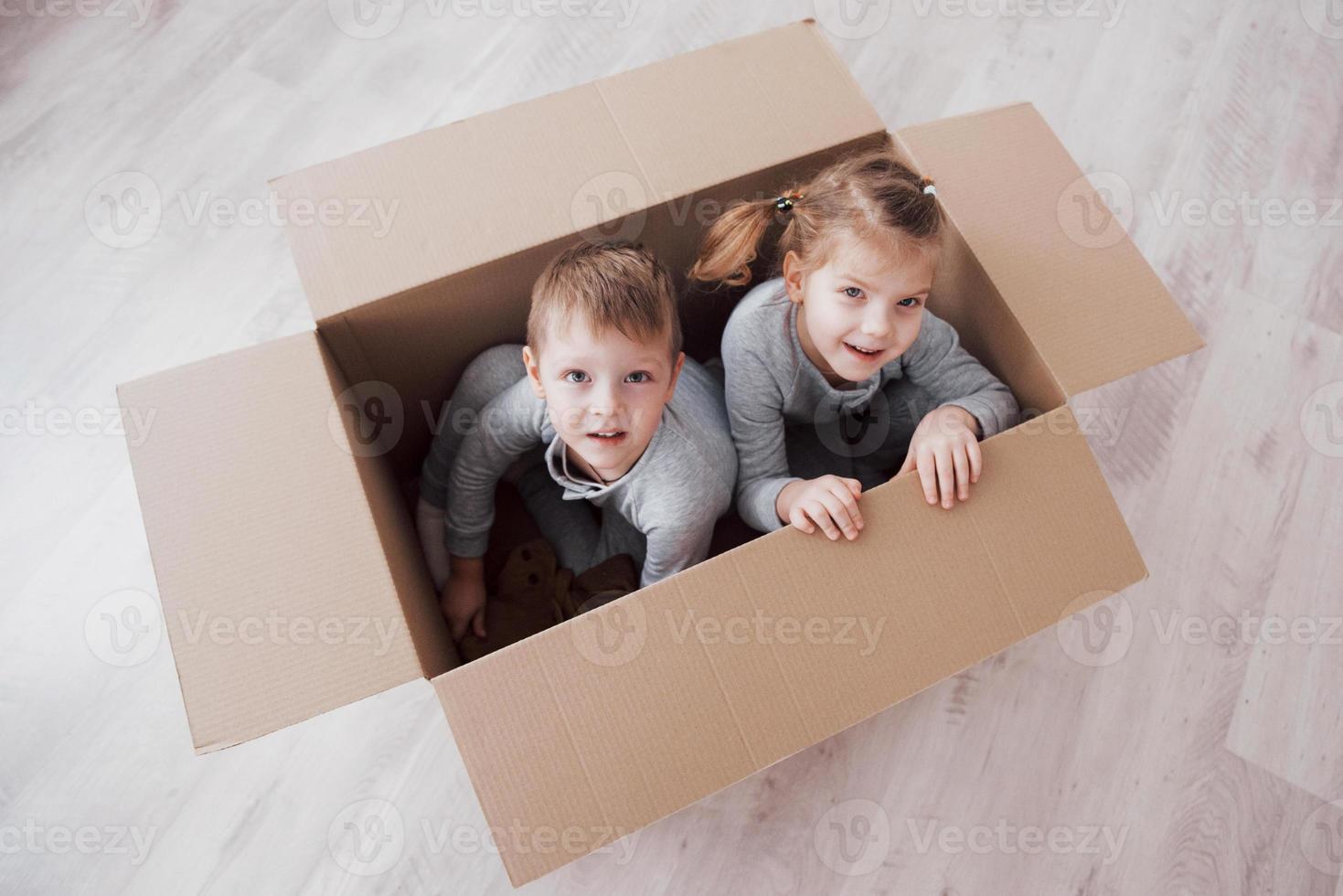 Baby brother and child sister playing in cardboard boxes in nursery photo