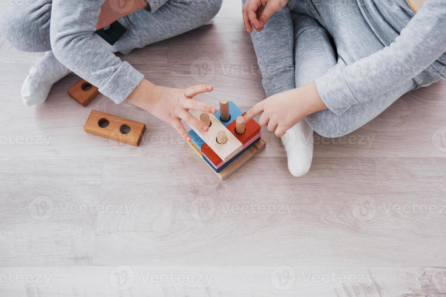 Los niños juegan con un diseñador de juguetes en el piso de la habitación de los niños. dos niños jugando con bloques de colores. juegos educativos de jardín de infantes foto