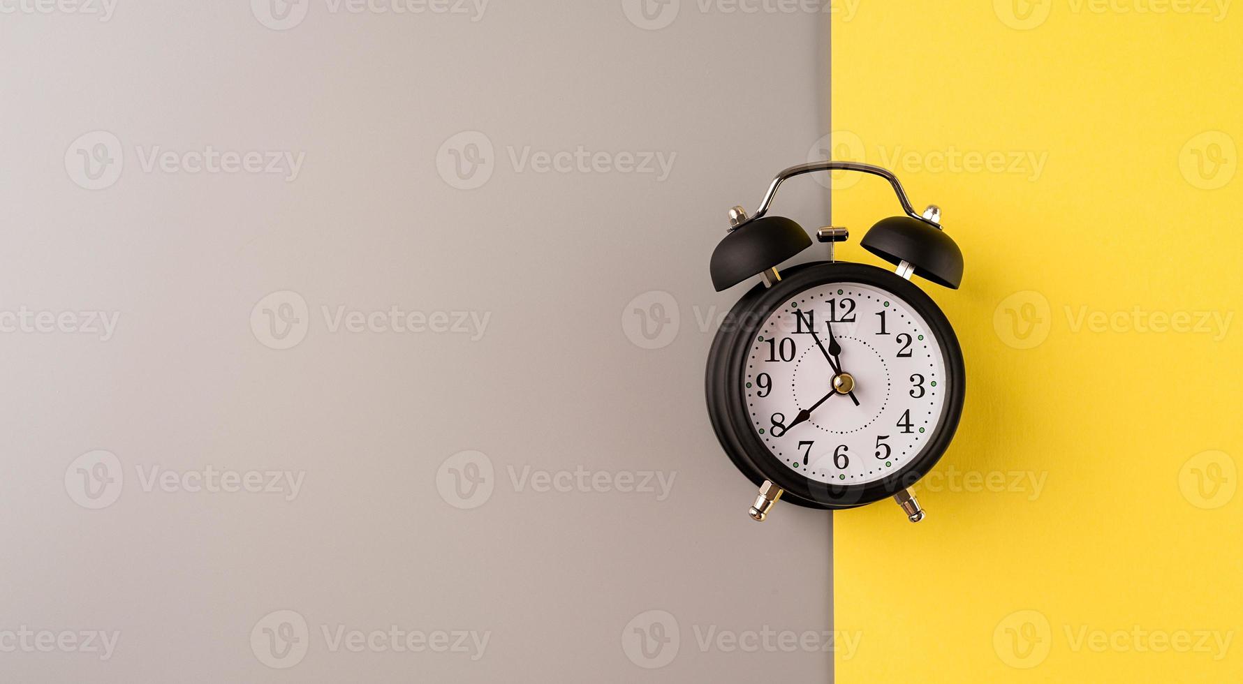 Black retro alarm clock isolated on double yellow and gray background with copy space photo