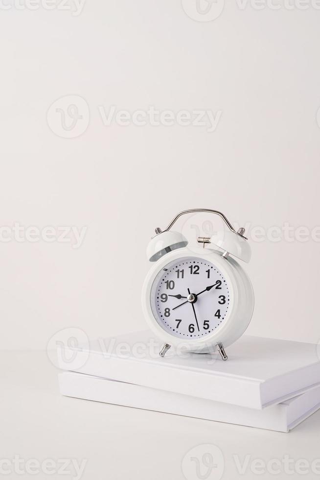 White alarm clock on stack of books, mockup design photo