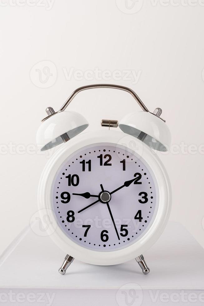 White alarm clock on stack of books, mockup design photo