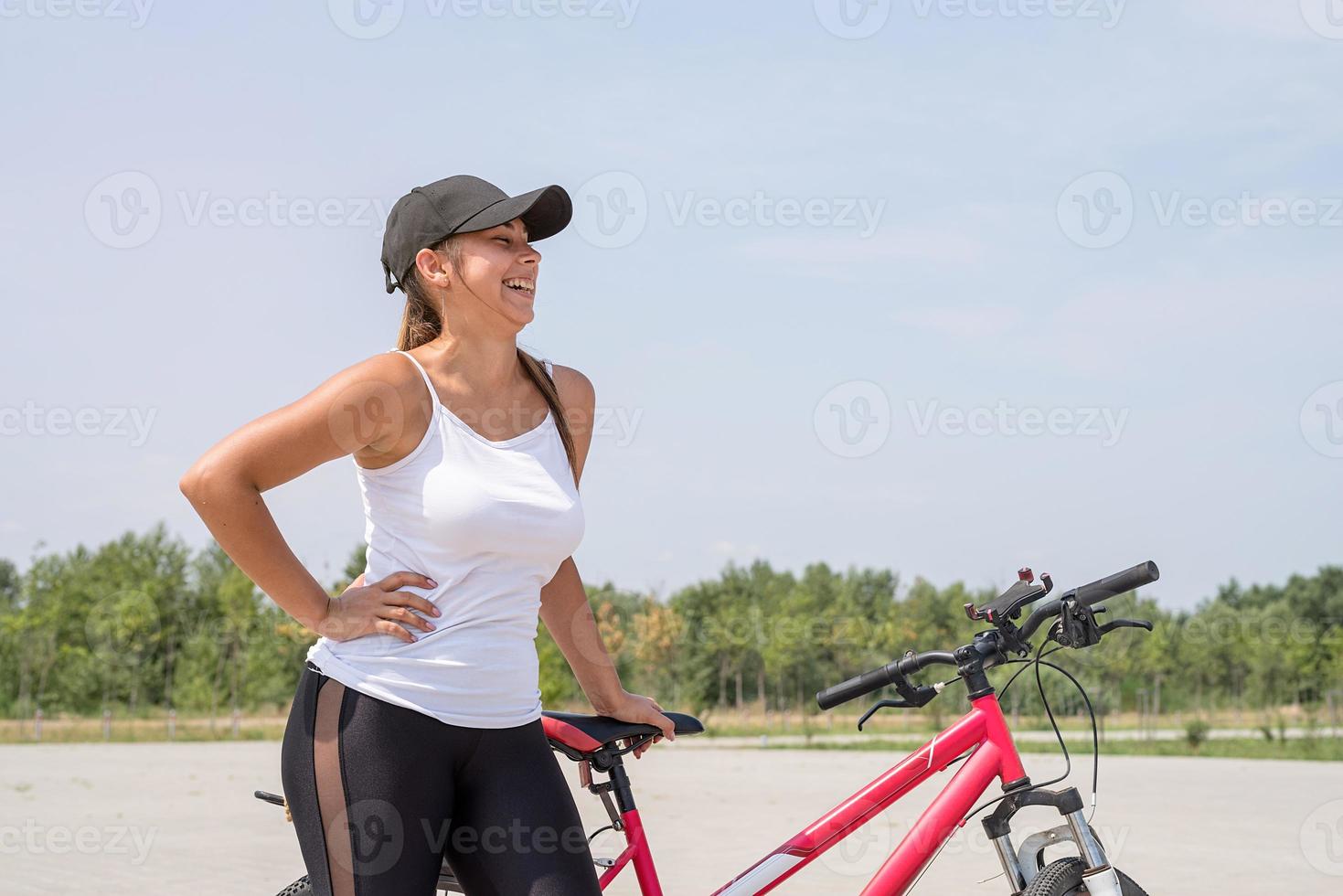 Carefree Woman riding a bike in a park and laughing photo