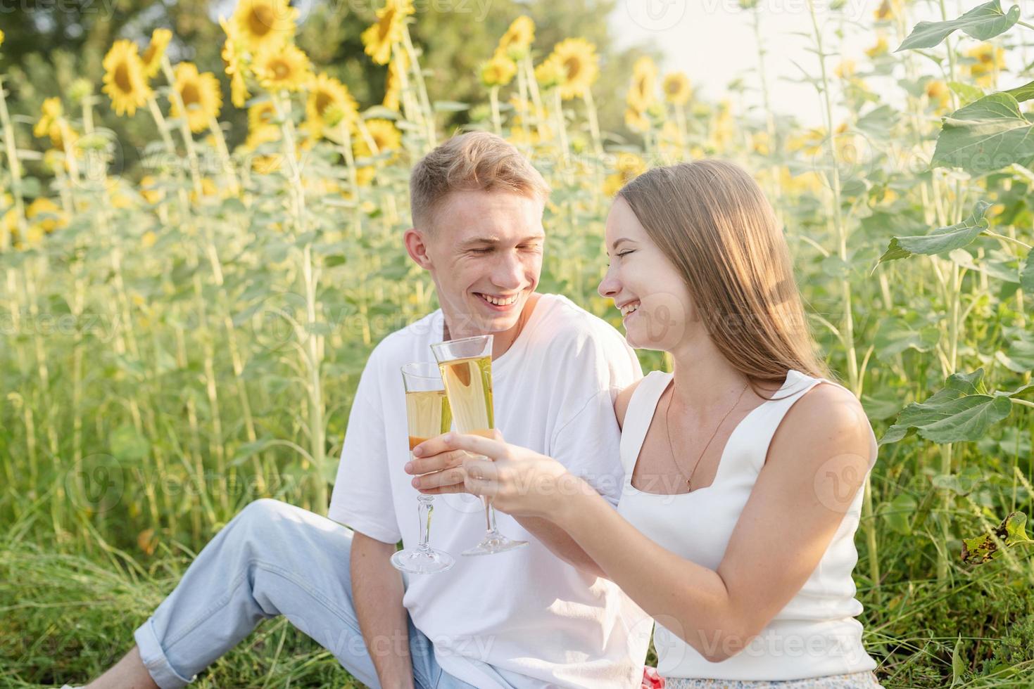 Pareja joven haciendo un picnic en el campo de girasol al atardecer foto