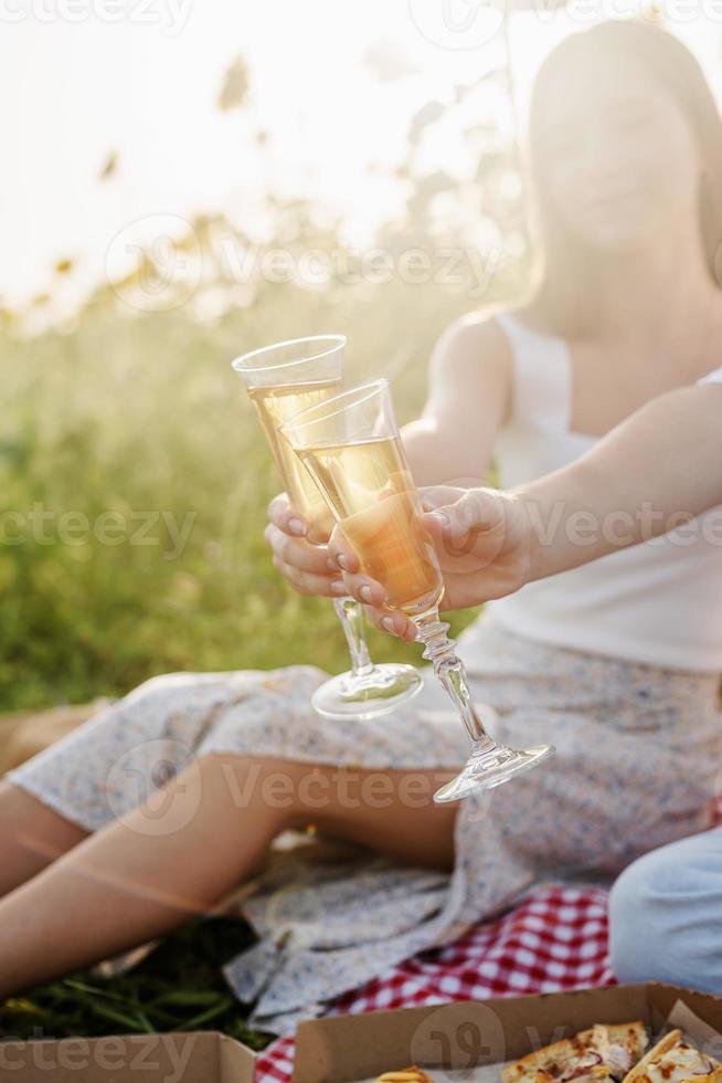 Young couple having picnic on sunflower field at sunset photo