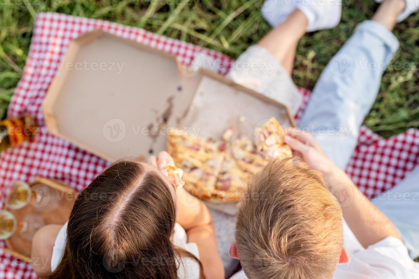 Pareja joven haciendo un picnic en el campo de girasol al atardecer foto