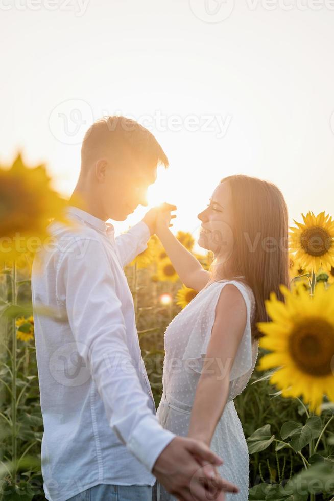 hermosa pareja divirtiéndose y bailando en campos de girasoles foto
