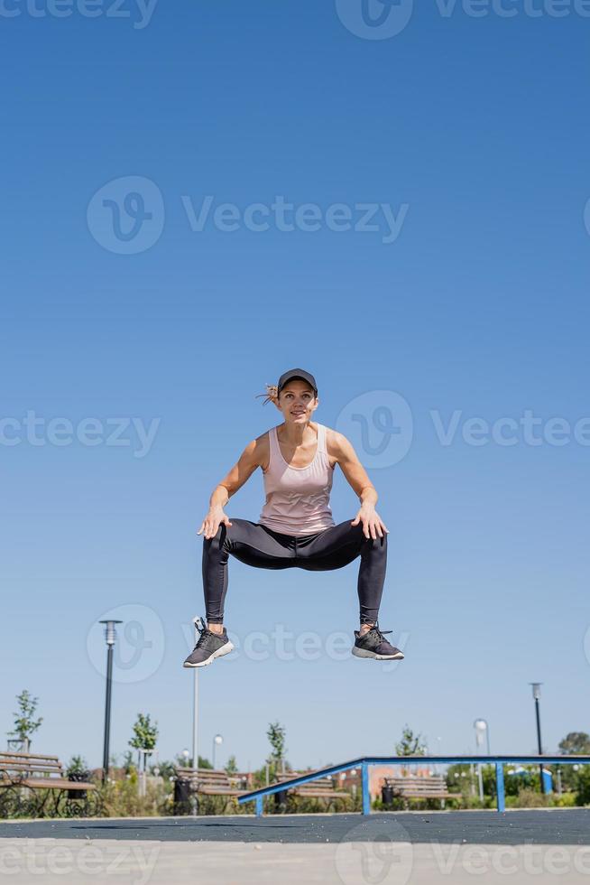 Sportive woman working out on the sports ground in sunny summer day photo