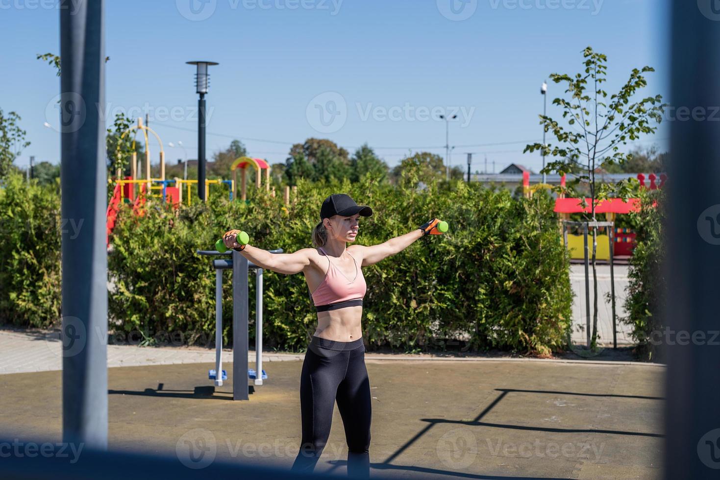 Sportive woman working out on the sports ground in sunny summer day photo