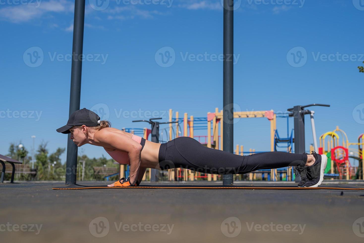 Sportive woman working out on the sports ground in sunny summer day photo