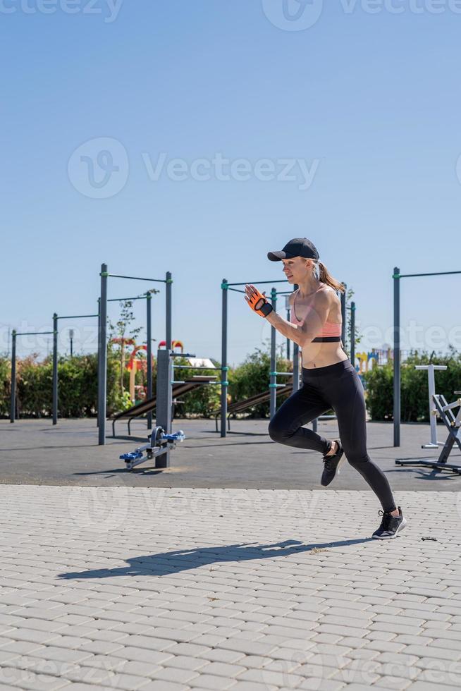 Sportive woman working out on the sports ground in sunny summer day photo