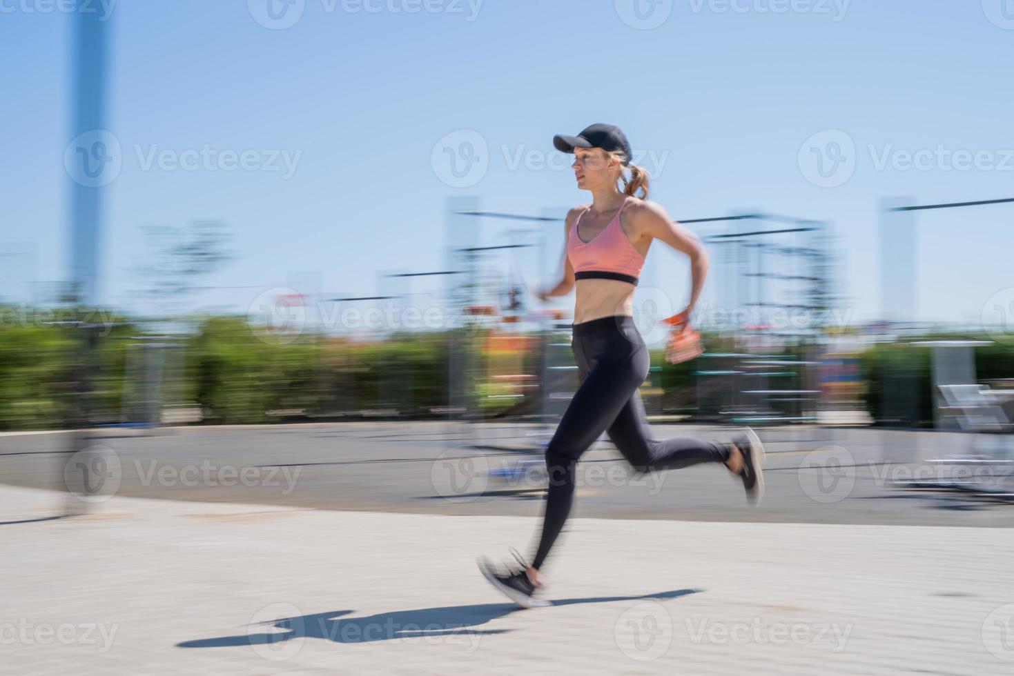 Sportive woman working out on the sports ground in sunny summer day photo