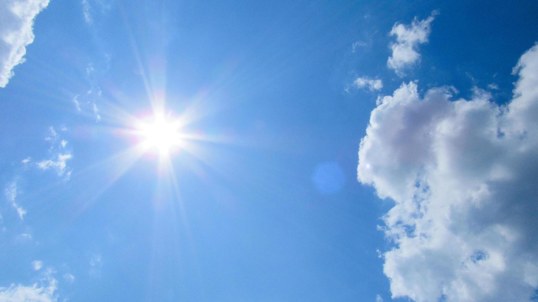 Sun, sky and clouds. Sun on the background of a blue sky with white clouds photo