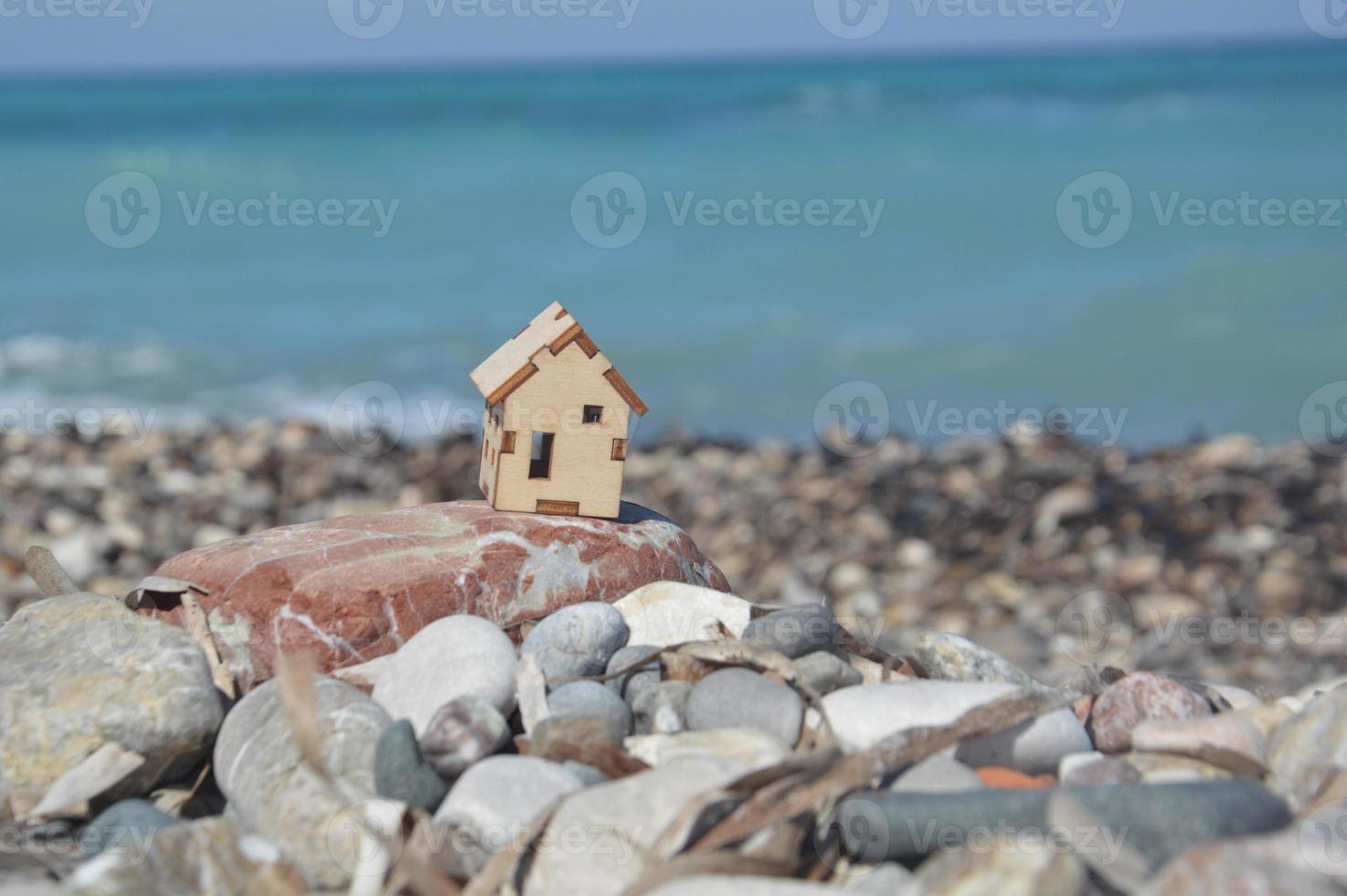 Small wooden mock-up of a house on the background of the sea photo