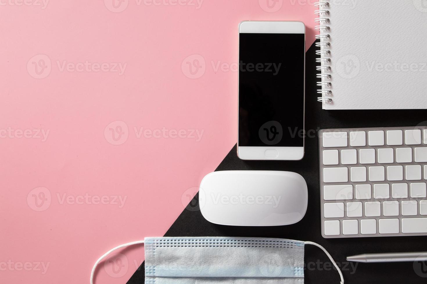 Flat lay desktop computer with keyboard, telephone, medical mask, notepad on colored background with copy space. Online education, work, business concept photo