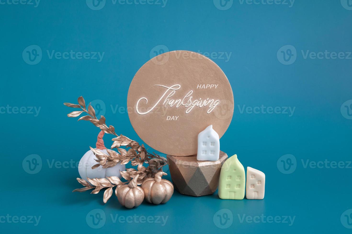 Still life of gold and white pumpkins, acorns and miniature houses on a turquoise background. Minimalistic autumn concept with text happy thanksgiving photo