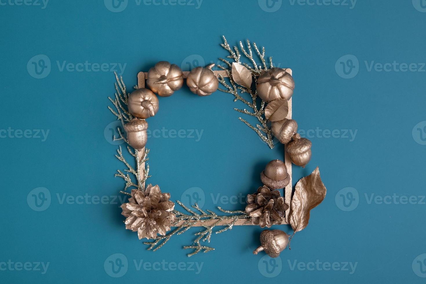 Flat lay golden pumpkins and acorns with frame for text on a turquoise background. Minimalistic thanksgiving day concept photo