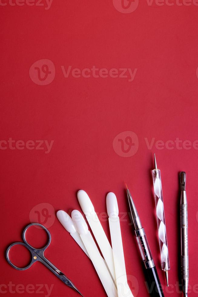 Manicure tools and tips for nail art on red background with copy space. Gel polish coating concept photo