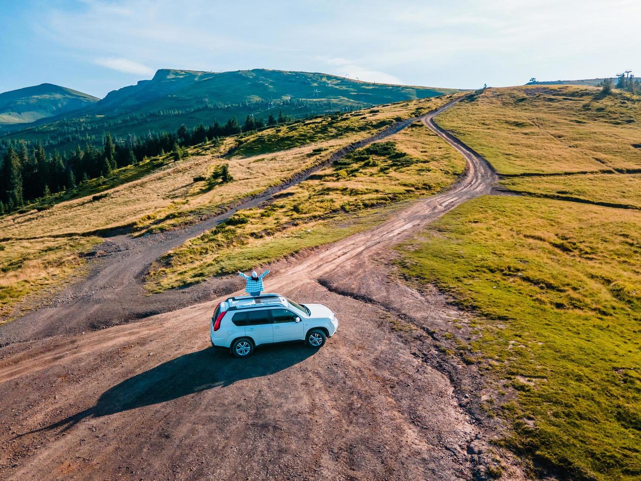 Aerial view of woman sitting on the roof of suv car photo