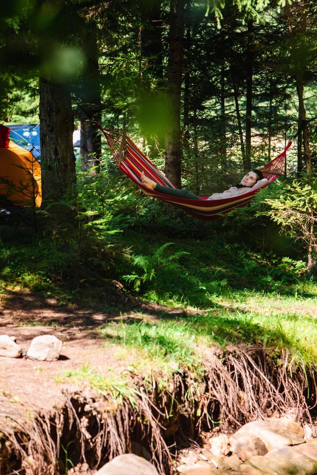 Woman laying down in hammock in the forest tent on background photo