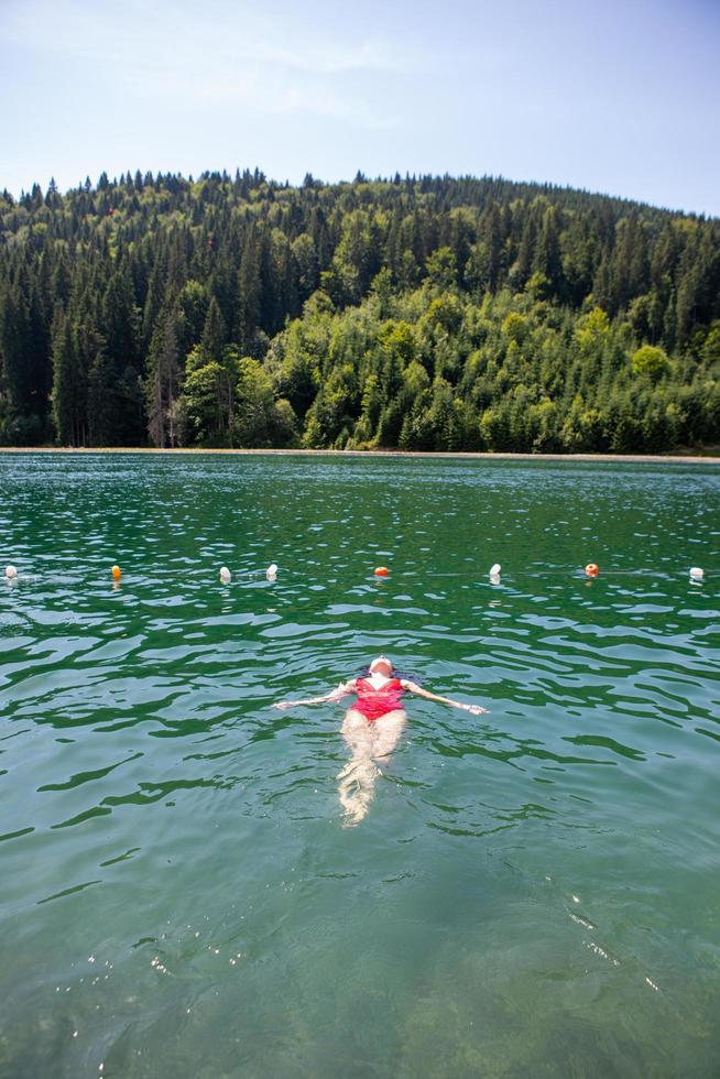 Woman floating on back in red swimsuit photo