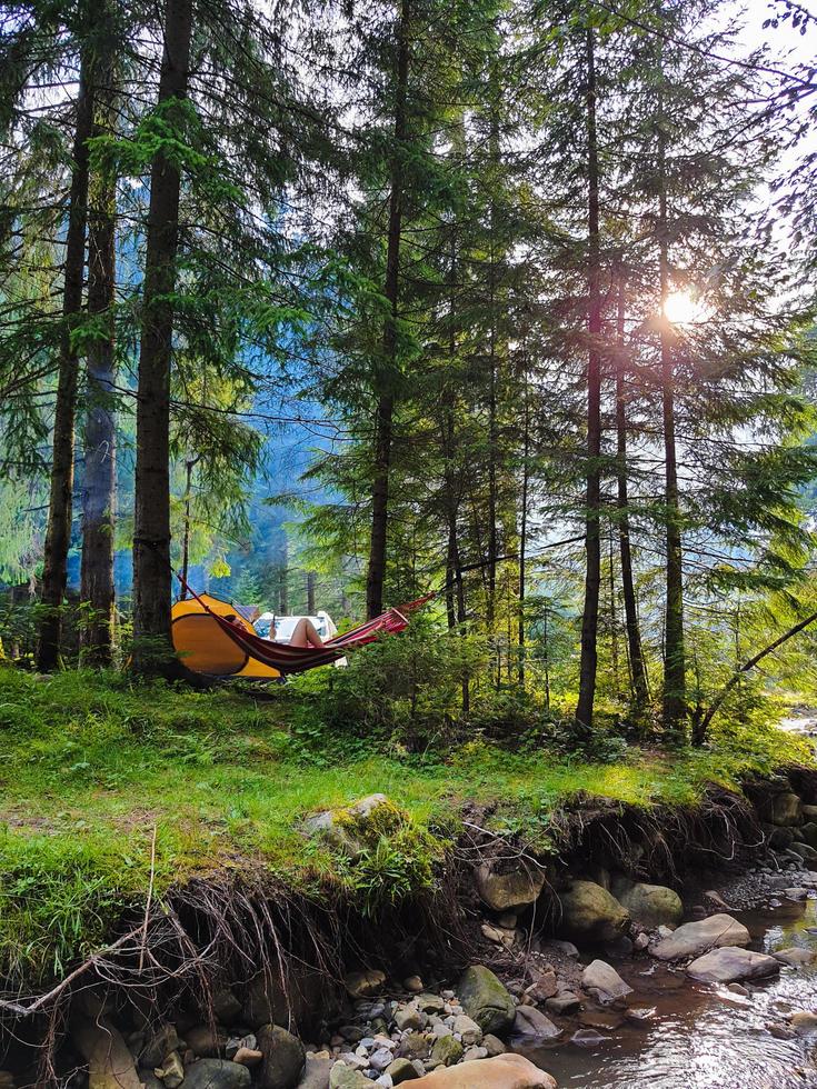 Woman resting laying on hammock at camping site photo