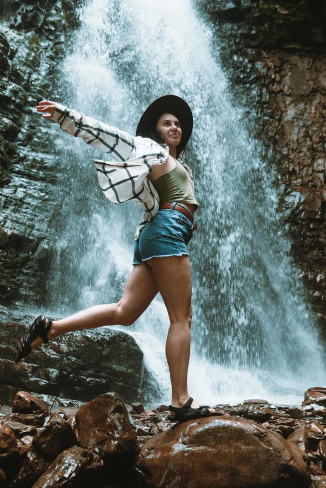 Mujer con sombrero marrón disfrutando de la vista de la cascada foto