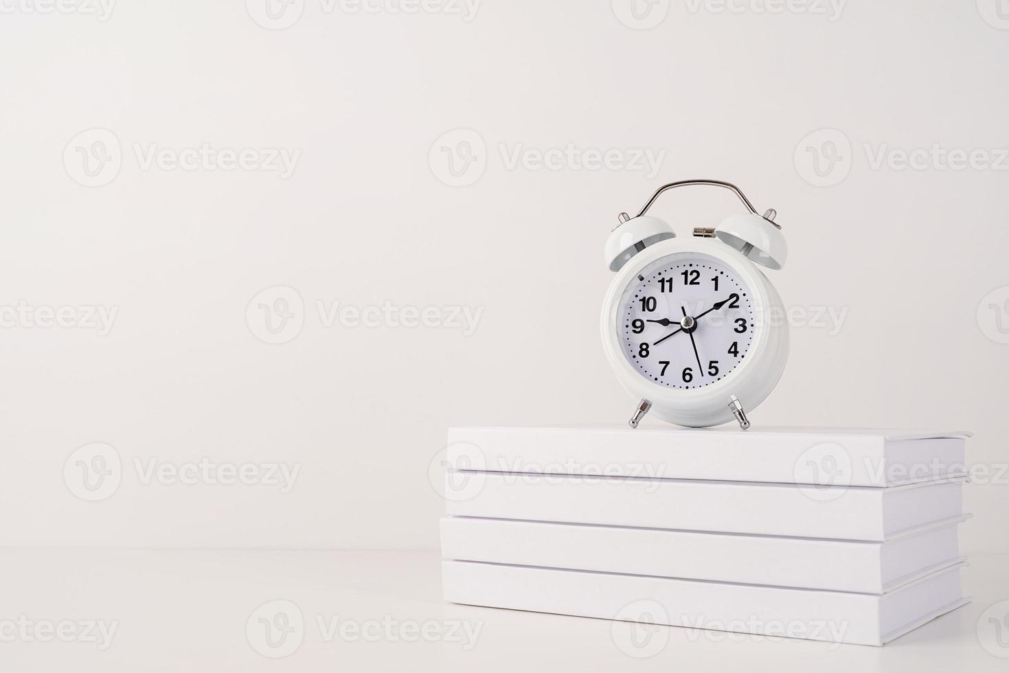 White alarm clock on stack of books, mockup design photo