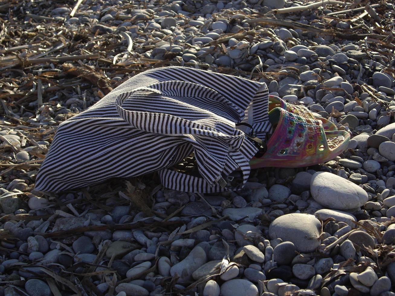 Beach slippers with a bag lie on stones photo