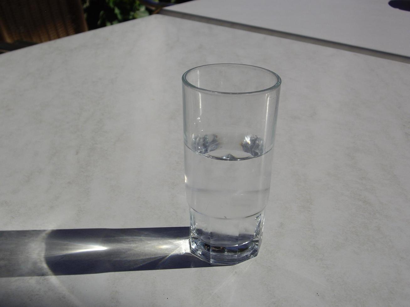A transparent glass with water stands on a white table photo